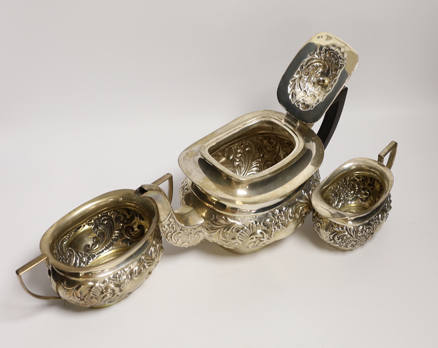 An Edwardian embossed silver three piece tea set, William Devonport, Birmingham, 1909